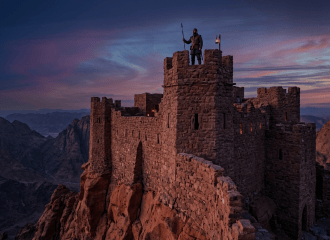 Guard holding spear on watchtower of stone fortress at sunset