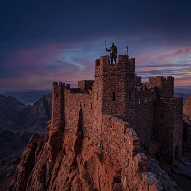 Guard holding spear on watchtower of stone fortress at sunset